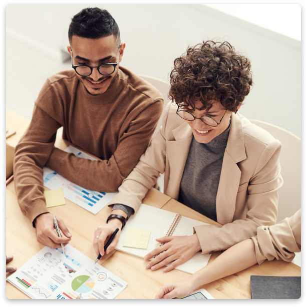 Two people sitting down pointing at content on a piece of paper